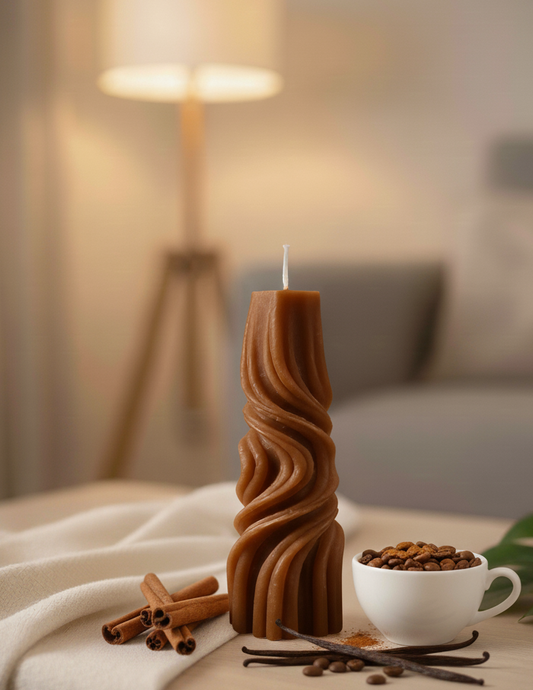 Candle with wavy design on a table with coffee beans, cinnamon sticks, and vanilla beans, set against a blurred indoor background.